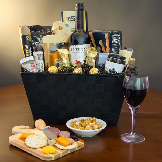 gourmet gift basket with wine, cheese, and snacks on wooden table