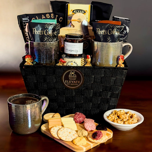 Gift basket with coffee, snacks, and a charcuterie board on a wooden surface.